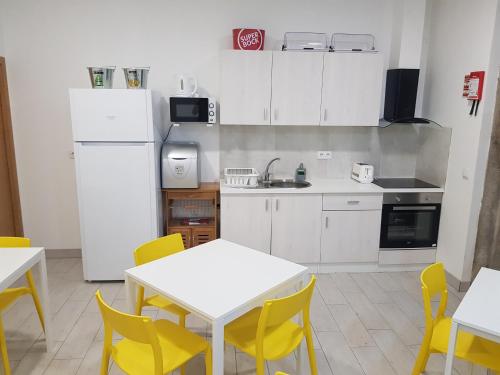 a kitchen with a table and chairs and a refrigerator at By Doors Hostel in Porto