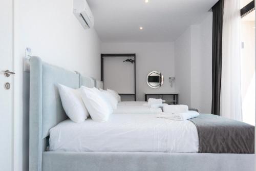 a white bedroom with a large bed with white pillows at Wait 'n Sea in Himare