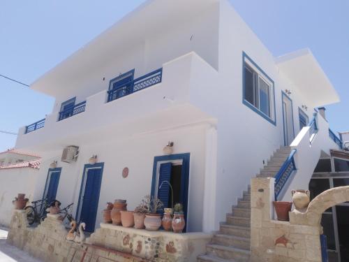 biały budynek z niebieskimi drzwiami i schodami z roślinami w obiekcie Mar Azul Σπίτι δίπλα στην παραλία και στο κέντρο! w Elafónisos