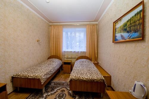 een kamer met 2 bedden en een raam bij Tri Peskarya Hotel in Koersk