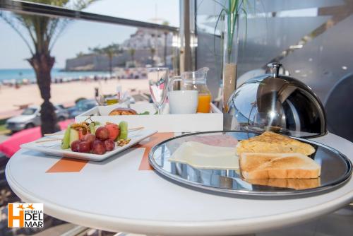 a table with a plate of food on a table with the beach at Hotel Boutique Estrella del Mar in Peñíscola