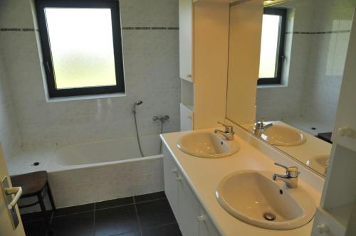 a bathroom with two sinks and a tub and a mirror at Gite Bouton d'Or in Heure