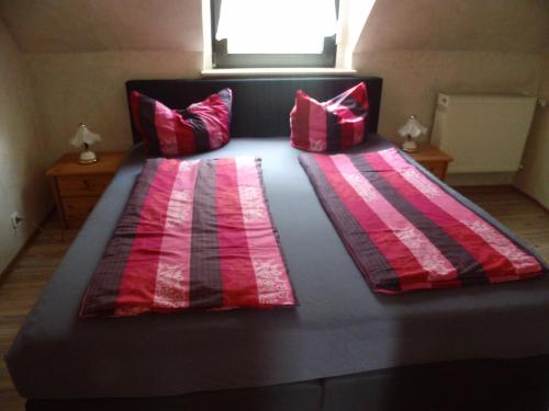a large bed with red and black sheets and pillows at Hotel Restaurant Zum Valwiger Herrenberg in Valwig