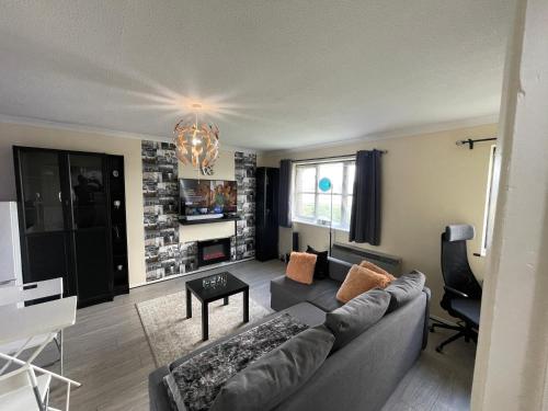 WindyS Basildon Smart Home في باسيلدون: غرفة معيشة مع أريكة وطاولة