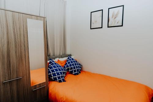 ein Schlafzimmer mit einem orangenen Bett mit zwei Kissen in der Unterkunft Regent park House in Etruria