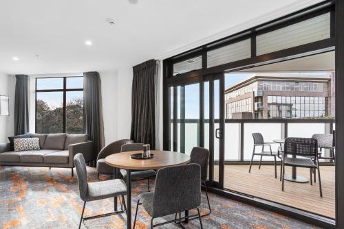 a living room with a couch and a table and chairs at Ramada by Wyndham Newmarket Auckland in Auckland