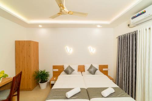 a bedroom with two beds and a ceiling fan at Oceana Hills Residency in Alleppey