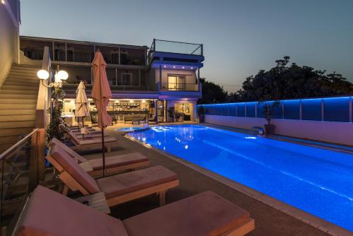 a swimming pool with chairs and a house at Denise Beach Hotel in Laganas