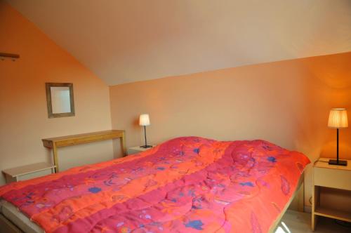 a bedroom with a bed with a red comforter at Villa Achille in Somme-Leuze