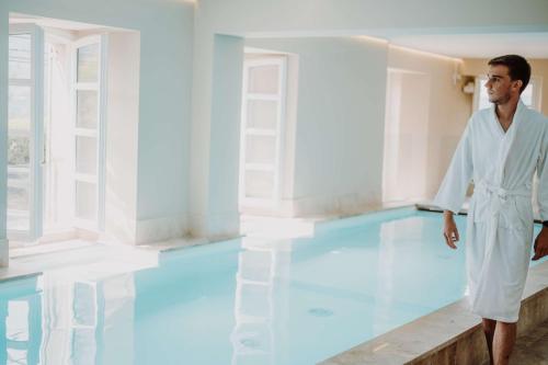 un hombre parado frente a una piscina en Hotel la Robeyere; BW Signature Collection, en Embrun