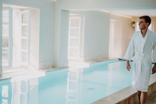 a man standing in front of a swimming pool at Hotel la Robeyere; BW Signature Collection in Embrun