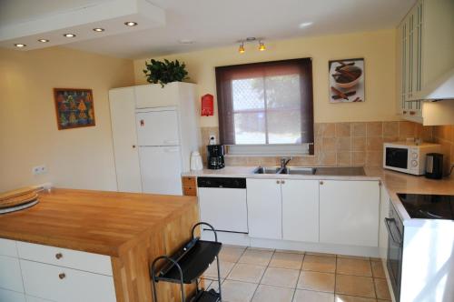 a kitchen with white cabinets and a wooden counter top at Villa Achille in Somme-Leuze