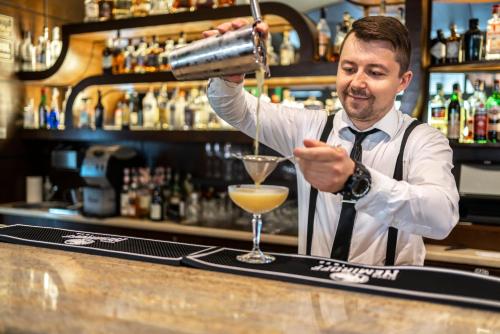 a bartender making a drink at a bar at Hotel Leda Spa - Adults Only in Kołobrzeg