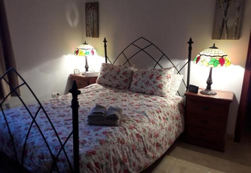 1 dormitorio con 1 cama con 2 lámparas y zapatos en Casa Margarita, en Algarinejo