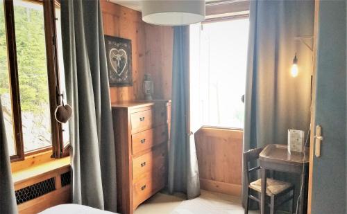 a bedroom with a window with blue curtains and a table at Chalet de Roselend in Beaufort