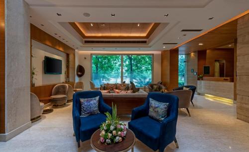 a living room with blue chairs and a couch at Hotel Saket 27 in New Delhi