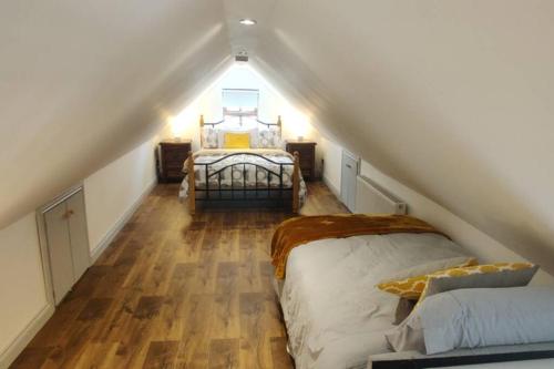 a attic bedroom with two beds and a staircase at Luxury 'Cois Abhainn' Self Catering Apartment in Foxford