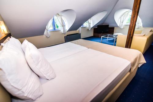 een slaapkamer met een bed met witte lakens en kussens bij Семеен хотел Анна-Кристина in Vidin
