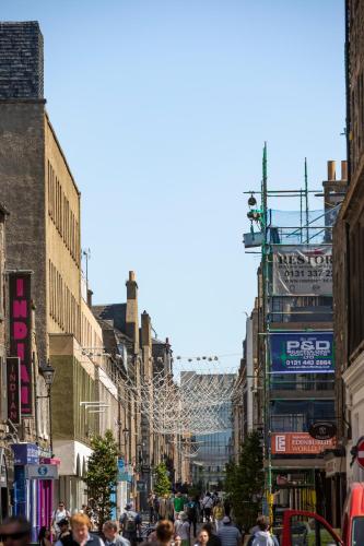 a crowd of people walking down a busy city street at The Edinburgh Rooftop Terrace in Edinburgh