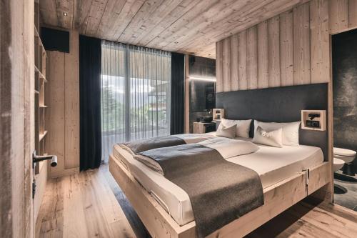 a bedroom with a large bed and a large window at Tenne Chalets in Racines