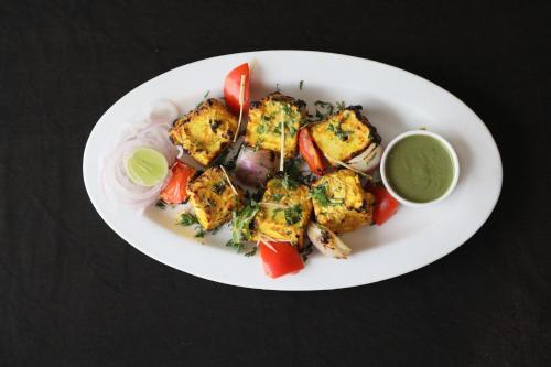 a white plate of food with vegetables and sauce at Hotel Saket 27 in New Delhi
