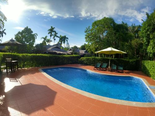 einen Pool mit 2 Stühlen und einem Sonnenschirm in der Unterkunft Cozy Garden Resort in Ao Nang Beach