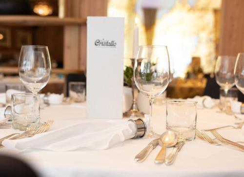 a table with wine glasses and silverware on it at Hotel Cristallo in Solda