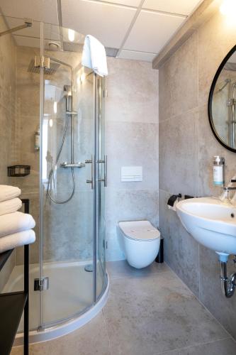 a bathroom with a shower and a sink and a toilet at Hotel Leda Spa - Adults Only in Kołobrzeg