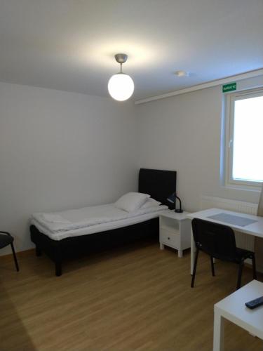 um quarto com uma cama, uma secretária e uma janela em Apartments Käyräkatu em Jyväskylä