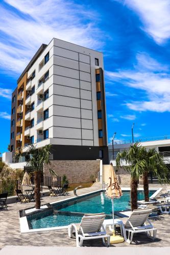 ein Hotel mit einem Swimmingpool mit Stühlen und einem Gebäude in der Unterkunft Eagles Apartments & Suites in Ulcinj