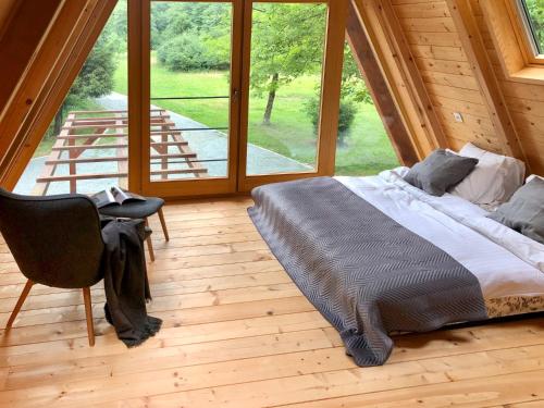 a bed and a chair in a room with a large window at Zen House in Brod na Kupi