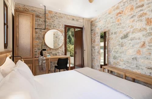a bedroom with a bed and a desk in a stone wall at The Authentic Village Boutique Hotel in Khóra Sfakíon