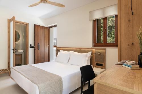 a bedroom with a white bed and a desk at The Authentic Village Boutique Hotel in Khóra Sfakíon