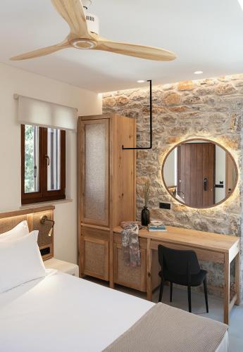 a bedroom with a bed and a desk and a mirror at The Authentic Village Boutique Hotel in Khóra Sfakíon