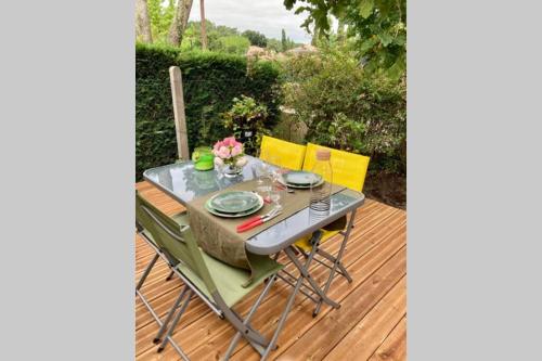 een tafel en stoelen op een houten terras bij Charmant chalet avec une grande terrasse au Pyla in La Teste-de-Buch