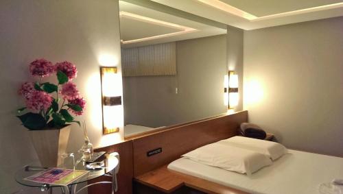a hotel room with a bed and a mirror at Motel Cisne Blumenau (Adult Only) in Blumenau