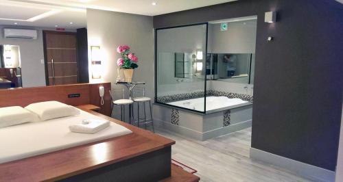 ein Bad mit einer Dusche, einem Bett und einer Badewanne in der Unterkunft Motel Cisne Blumenau (Adult Only) in Blumenau