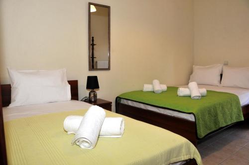 a room with two beds with green and white sheets at The Other Side of Meteora with lush garden, BBQ & pavillion in Kalabaka