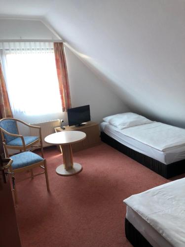 a room with two beds and a table and a chair at Ferienwohnung am Borgwallsee in Steinhagen