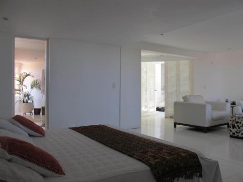 a white bedroom with a bed and a living room at Penthouse Caribbean View and private pool, Cartagena in Cartagena de Indias