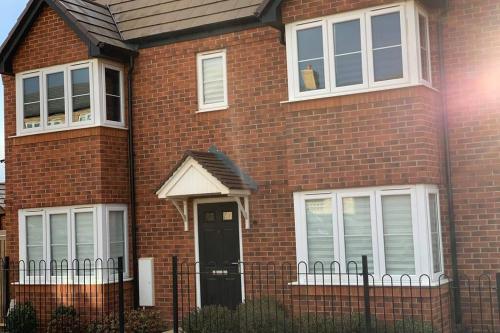 uma casa de tijolos vermelhos com uma porta preta em Stanton Cross 5 persons 3 Bed Home em Wellingborough