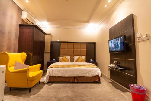 Habitación de hotel con cama y silla amarilla en مقصورة مرسال سويت, en Riad