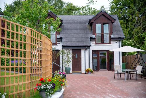 a wooden fence in front of a house with a patio at Braeside Guest House, Loch Lomond in Drymen