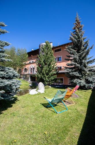 two chairs sitting in the grass in front of a building at Hotel Galli in Livigno