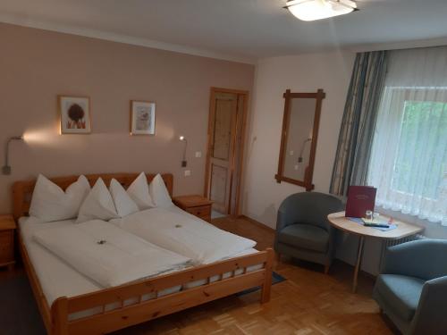 a bedroom with a bed and a chair and a table at Pension Isabella in Bad Kleinkirchheim