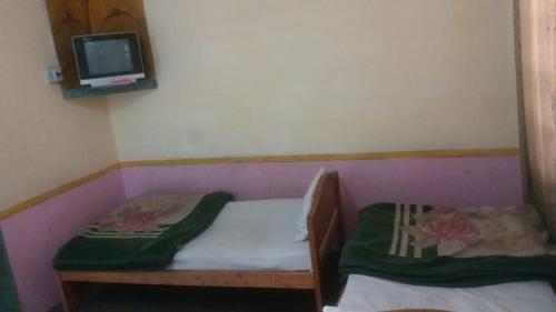 Hotel Chitral Continental في شيترال: غرفة صغيرة مع سرير صغير وتلفزيون
