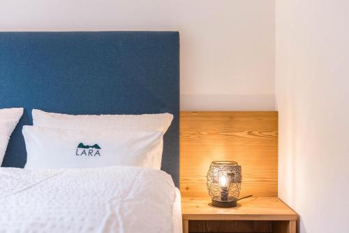 a bed with a blue headboard and a candle on a table at Apt Lara Siela in Ortisei