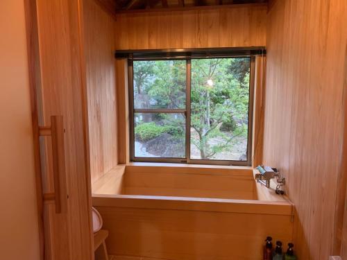 a bathroom with a bath tub and a window at オーベルジュ美の浜 流石 in Kasaoka