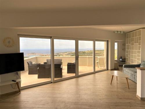 a living room with sliding glass doors with a view of the ocean at Apartments Carpe Diem in Primošten