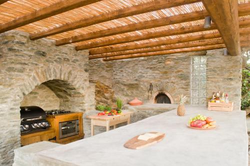 uma cozinha exterior com uma mesa e uma parede de pedra em Sifnos Roots em Exámbela